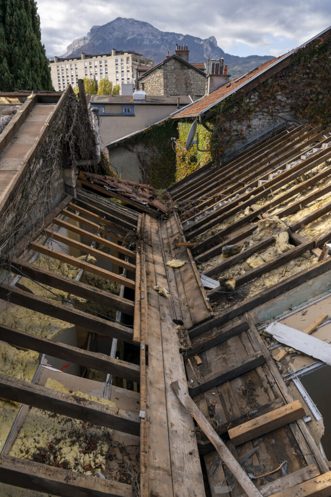 La charpente apparente d'une toiture laissant voir la laine de verre déchirée - Agrandir l'image, fenêtre modale